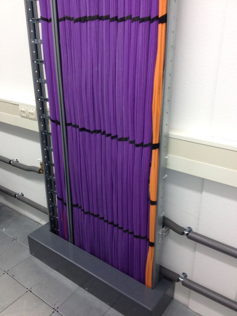 Vertical purple and orange cable bundles secured in a metal tray