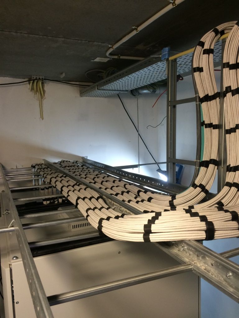 Yellow data cables entering a cabinet from wall-mounted trays