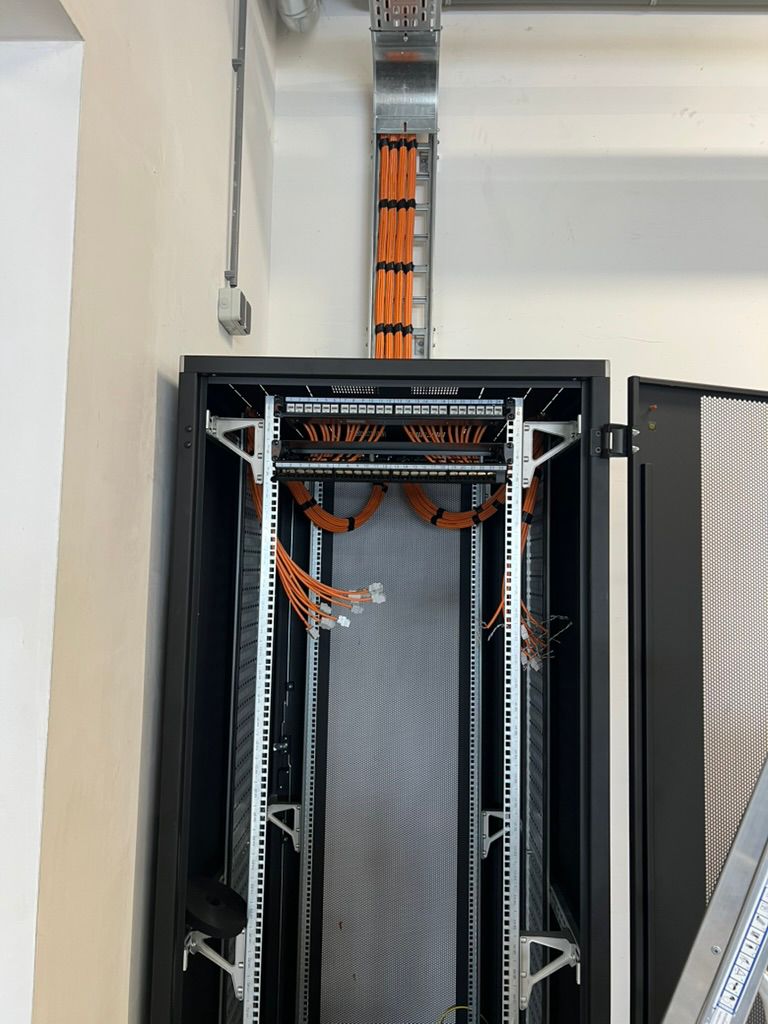 Orange cables terminated into patch panels in a black rack